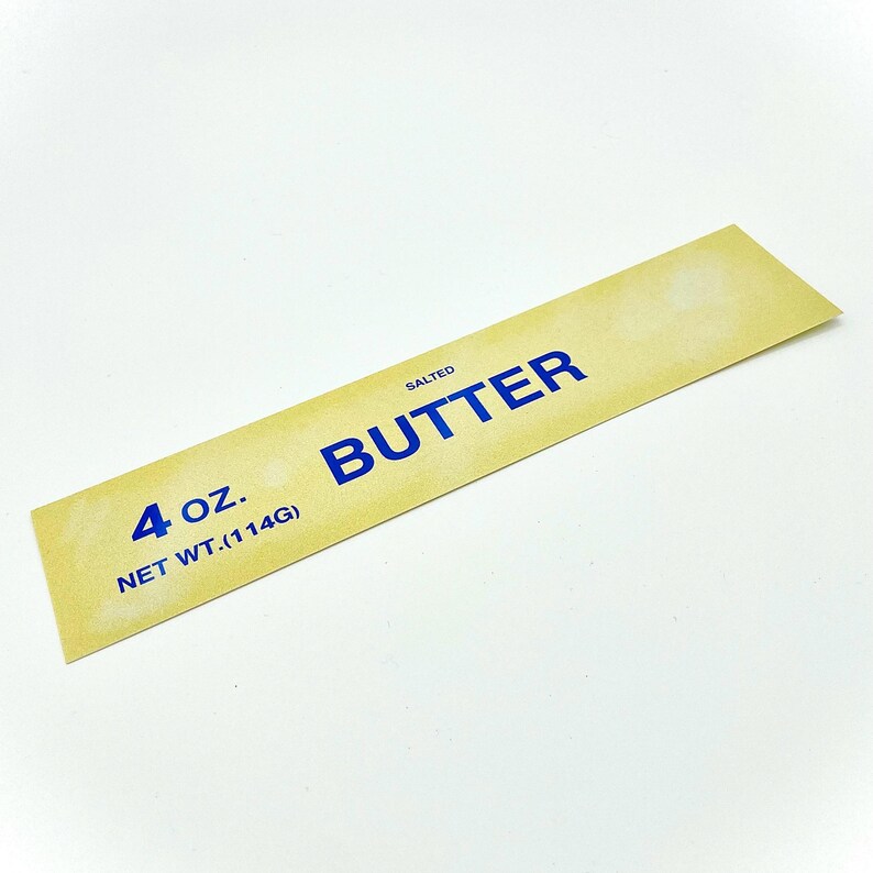 May include: A yellow rectangular label with blue text that reads "SALTED BUTTER" and "4 oz. NET WT. (114G)".
