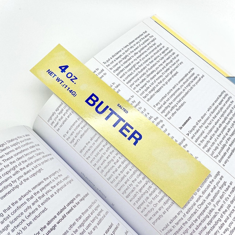 May include: A yellow bookmark with the words "SALTED BUTTER" in blue lettering. The bookmark is 4 ounces and has a watercolor-style design.