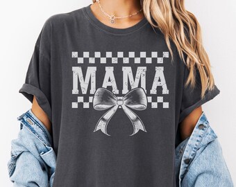 Op de afbeelding: Een antracietkleurig T-shirt met een witte geruite rand en het woord "MAMA" in wit met een witte strik in het midden.