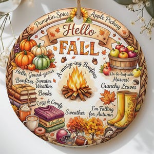 May include: A round ceramic ornament featuring a fall-themed illustration with the text Hello FALL. The design includes pumpkins, a bonfire, a basket of apples, books, mugs, a sweater, yellow rain boots, and autumn leaves with various seasonal phrases.