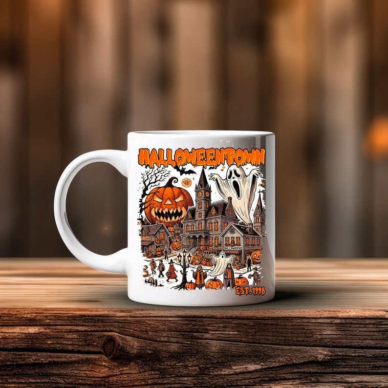 May include: White ceramic coffee mug with a Halloween-themed design. The design features a spooky town with a haunted house, a ghost, and a jack-o'-lantern. The text "Halloweentown Est. 1978" is printed on the mug.