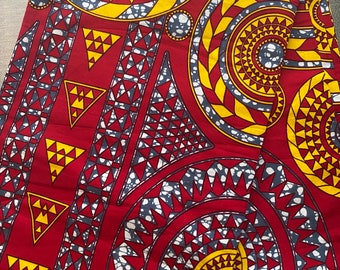 Könnte beinhalten: Roter und gelber Stoff mit einem geometrischen Muster aus Kreisen, Dreiecken und Spiralen.