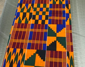 Könnte beinhalten: Ein lebendiger Stoff mit Muster, der eine Mischung aus geometrischen Formen und Linien aufweist. Das Design enthält die Farben Orange, Blau, Grün, Schwarz und Burgunderrot. Der Stoff wird wahrscheinlich für Kleidung oder Heimdekoration verwendet.