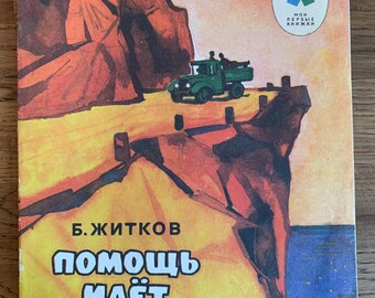 May include: A vintage children's book cover with an illustration of a green truck driving on a dirt road. The book title is "Помощь идёт" by B. Житков. The cover is yellow, orange, and blue with a red rock cliff in the background.