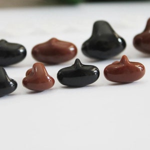 May include: Assortment of black and brown plastic safety eyes for crafts. The eyes are in various sizes and shapes, with some having a pointed top.