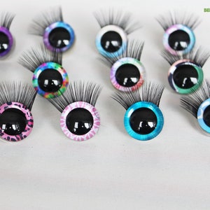 May include: Assortment of ten colorful googly eyes with eyelashes. Each eye has a black pupil and a different patterned design, including tie-dye, leopard print, and polka dots.