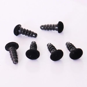 May include: A collection of six black screws with a flat, round head and a threaded shaft. The screws are arranged on a white surface, showcasing their design and construction. Ideal for woodworking or general repair.
