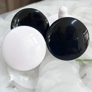 Peut inclure: Gros plan sur des yeux de sécurité en plastique noir et blanc pour l'artisanat. Les yeux sont ronds et ont une finition brillante. Les yeux sont sur un fond blanc.