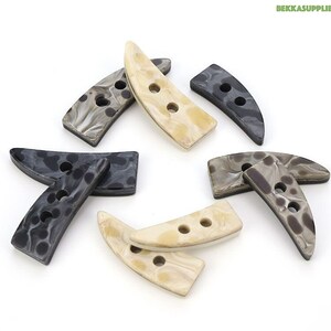 May include: Assortment of eight horn-shaped buttons in black, brown, and cream with a marbled pattern. Each button has two holes.