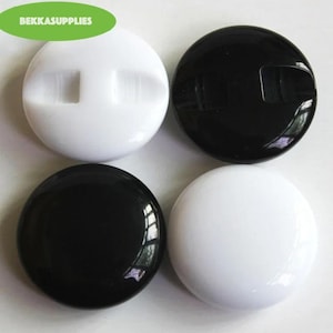 May include: Four round buttons, two black and two white. Each button has a raised, rectangular design in the center.