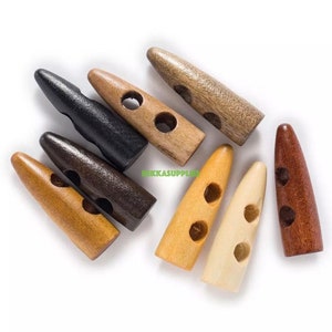 May include: Assortment of wooden toggle buttons in various colors and finishes, including natural wood, brown, black, and red. Each button has two holes and a pointed tip.