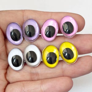 May include: Eight colorful, oval-shaped craft eyes in shades of purple, pink, white, and yellow. Each eye has a glossy, clear surface with a large, black pupil. These plastic eyes are ideal for various DIY projects.