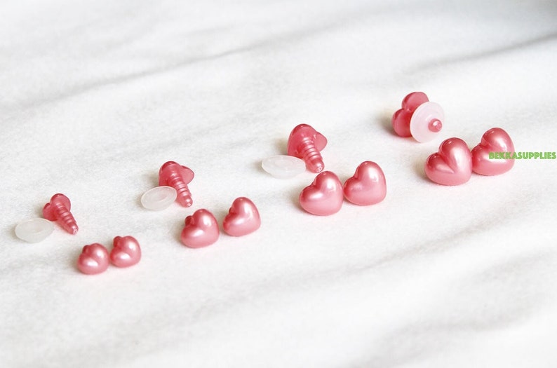 May include: Assortment of pink heart-shaped plastic safety eyes with white plastic washers and screws for plush toy making.
