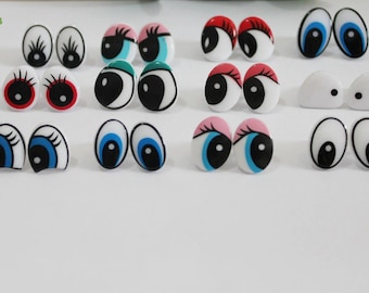 May include: Assortment of plastic googly eyes in various colors and designs, including blue, red, green, and black. The eyes are oval-shaped and have white scleras with painted pupils and eyelashes.