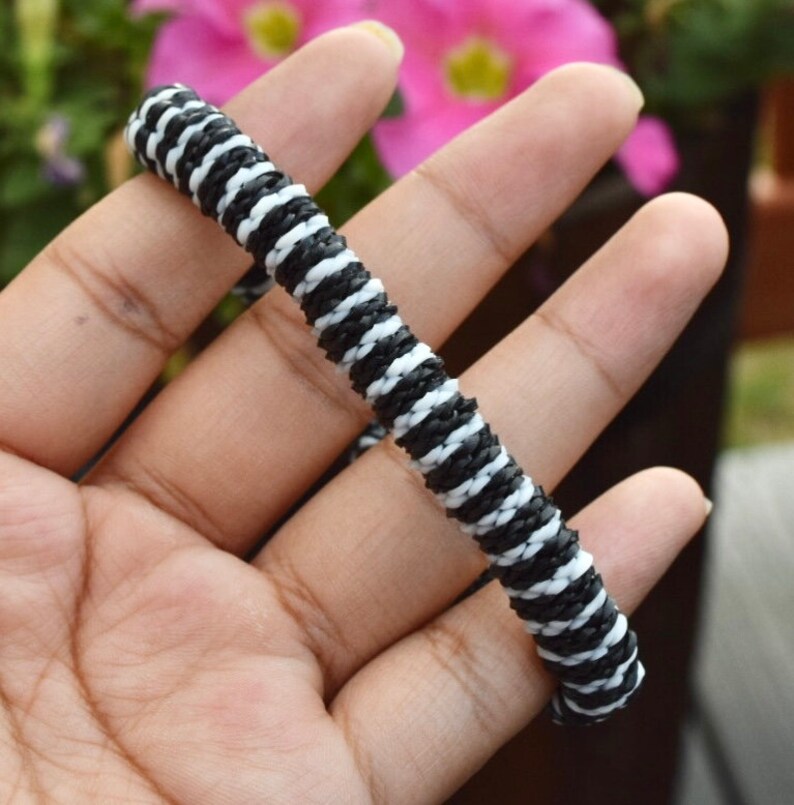 May include: A black and white striped bracelet made of woven cord.