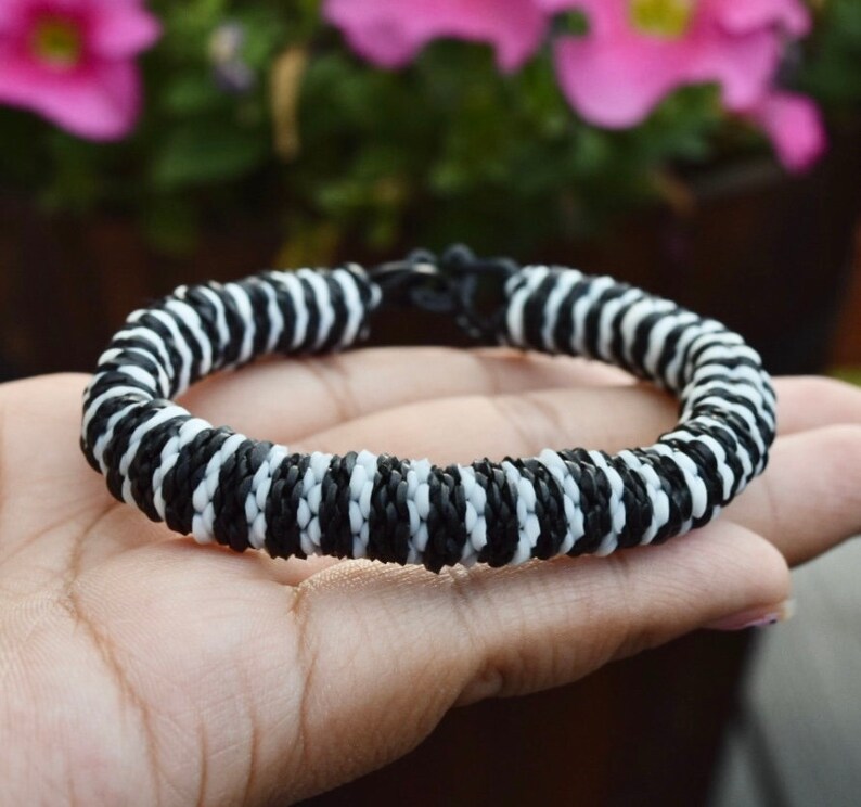 May include: Black and white striped bracelet made of woven cord.