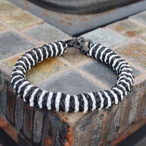 May include: Black and white striped bracelet with a metal clasp.