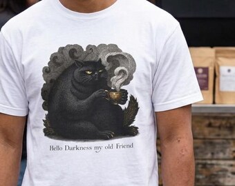 May include: A white short-sleeve t-shirt featuring a graphic of a black cat holding a steaming mug with the text "Hello Darkness my old Friend" printed underneath the illustration. The design is centered on the chest of the garment.