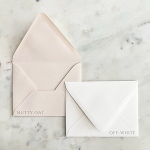 May include: Two envelopes, one open and one closed, on a marble surface. The open envelope is a light beige color with the text "NUTTY OAT" printed on it. The closed envelope is off-white with the text "OFF-WHITE".