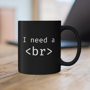 Peut inclure: Une tasse à café noire avec du texte blanc qui dit "I need a <br>" sur une surface en bois.