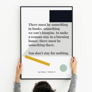 Peut inclure: Une affiche encadrée avec un cadre noir, présentant une citation de Fahrenheit 451 de Ray Bradbury. Le texte est sur fond blanc avec des formes géométriques en marine, gris, or et vert. L'affiche est tenue par une personne.