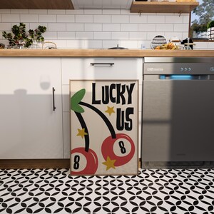 Może przedstawiać: Kremowy plakat z tekstem "Lucky Us" czarnymi literami. Przedstawiono dwie czerwone wiśnie z zielonymi szypułkami i ż&oacute;łtymi gwiazdami, każda z białą cyfrą "8".