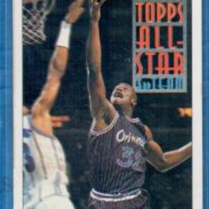 May include: A Topps All-Star basketball card featuring Shaquille O'Neal in an Orlando Magic jersey, number 32. The card has a blue border and the text "Topps All-Star" in the upper right corner. The player is reaching for the ball.