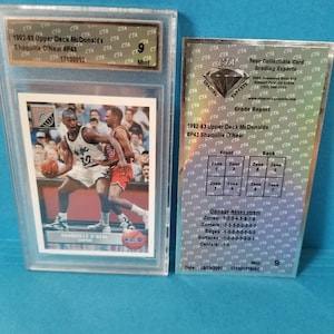 May include: A graded trading card of Shaquille O'Neal from the 1992-93 Upper Deck McDonalds series. The card is in a protective case and has a grade of 9. The card features a photo of Shaquille O'Neal in a basketball uniform.