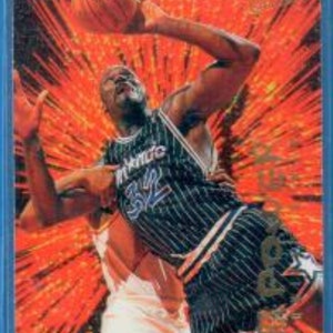 May include: A basketball player wearing a blue and white striped jersey with the word "Magic" on the front, is jumping up to shoot a basketball. The background is a red and orange burst of light.