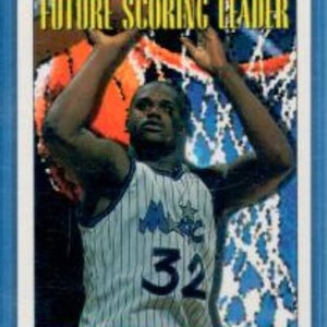 May include: A basketball trading card featuring a photo of Shaquille O'Neal in a blue and white Orlando Magic jersey with the number 32. The card has a blue border and the text "TOPP'S FUTURE SCORING LEADER" in pink and white.