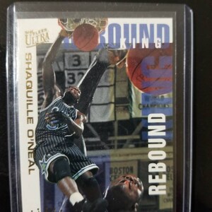 May include: A basketball trading card featuring Shaquille O'Neal in a blue and white Orlando Magic uniform, with the text "Rebound King" and "Ultra" on the card.