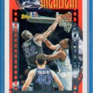 May include: A 1992-93 Topps basketball card featuring Shaquille O'Neal in a blue and white Orlando Magic uniform. The card has a red, white and blue film strip design with the word "HIGHLIGHT" in bold letters.