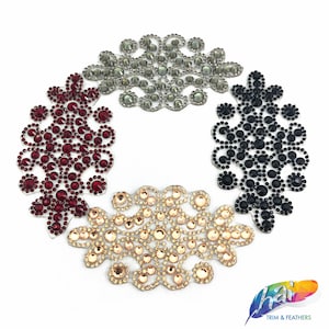 May include: Four rhinestone embellishments in different colors: red, black, gold, and gray. Each embellishment is shaped like a floral design with a circular pattern.