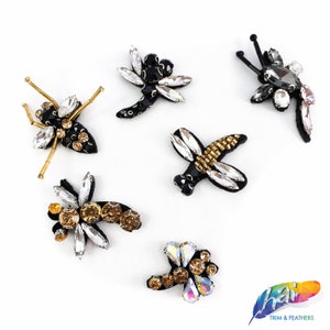May include: Assortment of six colorful dragonfly-shaped embellishments with iridescent rhinestones and black bead accents. These decorative embellishments are perfect for adding a touch of sparkle to clothing, accessories, and crafts.