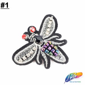 May include: Black embroidered bee applique with silver thread, rhinestones, and iridescent beads. The bee has red and black eyes and a black body.