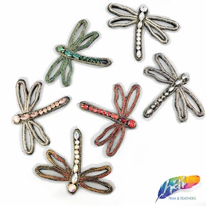 Op de afbeelding: Zes geborduurde libellenapplicaties in verschillende kleuren, waaronder groen, rood en goud, met kristallen versieringen. De applicaties zijn op een zwarte mesh-achtergrond.