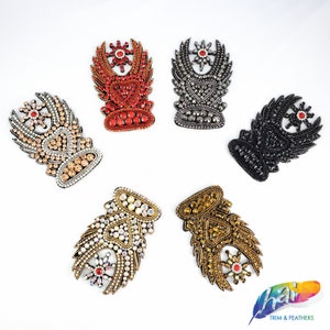 May include: Six different colored embroidered patches with a heart and wings design. The patches are decorated with rhinestones and beads. The patches are available in red, black, gold, silver, and two shades of gold.