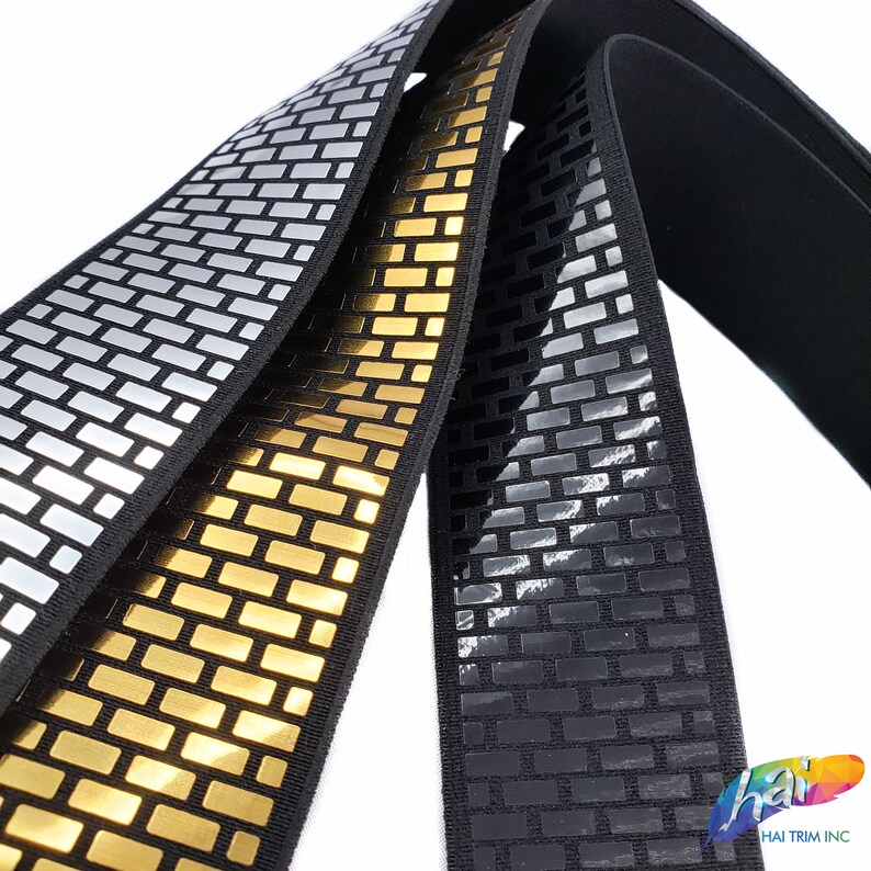May include: Three rolls of reflective elastic trim with a brick pattern. The trim is available in silver, gold, and black.