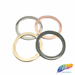 May include: Four metal rings in different finishes: silver, gold, rose gold, and black. The rings are stacked on top of each other.