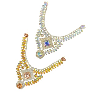 May include: Two iridescent crystal necklaces with gold accents. One necklace is a choker style with a square-shaped crystal in the centre. The other necklace is a longer style with a square-shaped crystal in the centre.