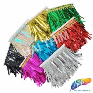 May include: Assortment of metallic fringe trim in various colors, including gold, green, red, iridescent, black, turquoise, pink, and silver. The trim is arranged in a fan shape, with the gold trim at the top and the silver trim at the bottom.