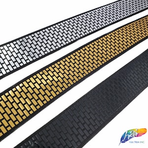 May include: Three rolls of black elastic trim with a silver, gold, and black brick pattern. The trim is reflective and has a shiny finish.