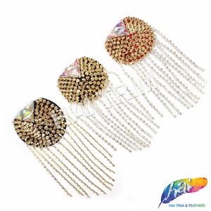 Puede incluir: Tres adornos redondos de color dorado, engastados con piedras preciosas, con cadenas colgantes de diamantes de imitación. Cada adorno tiene una base de color diferente: rojo, negro y negro.