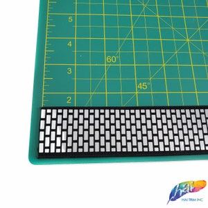 May include: Black and silver elastic trim with a geometric pattern. The trim is shown on a green cutting mat with markings for 45 and 60 degrees.