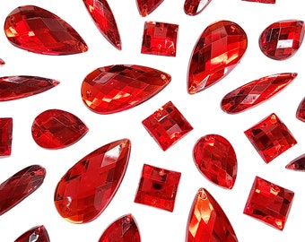 May include: Assortment of red glass rhinestones in various shapes and sizes, including teardrop, square, and oval.