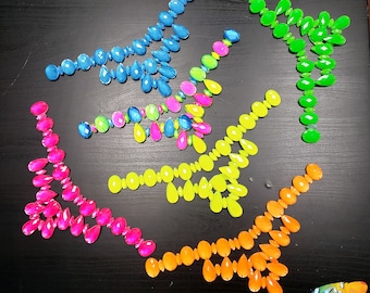 May include: Assortment of colorful, iridescent, teardrop-shaped rhinestones arranged in necklace shapes. The rhinestones are in shades of blue, green, yellow, orange, and pink.