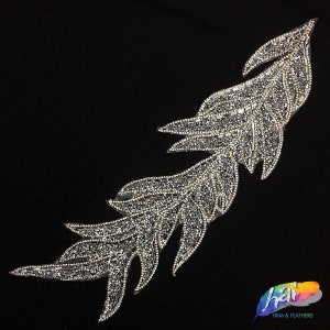 May include: A silver feather-shaped embellishment with a sparkly, beaded design. This trim is perfect for adding a touch of glamour to clothing, accessories, or home decor projects.