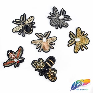 May include: Six embroidered bee and spider appliques with rhinestones. The appliques are in various colors, including black, gold, and silver.