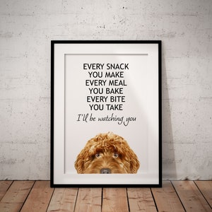 May include: A white framed print with a brown dog peeking out from the bottom. The text reads "Every snack you make, every meal you bake, every bite you take, I'll be watching you."