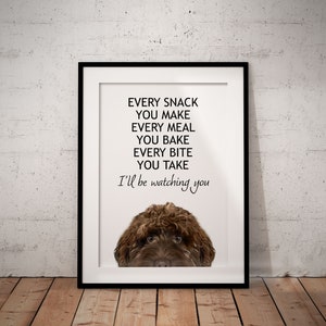 May include: A white framed print with a brown dog peeking out from the bottom. The text on the print reads "EVERY SNACK YOU MAKE EVERY MEAL YOU BAKE EVERY BITE YOU TAKE I'll be watching you"